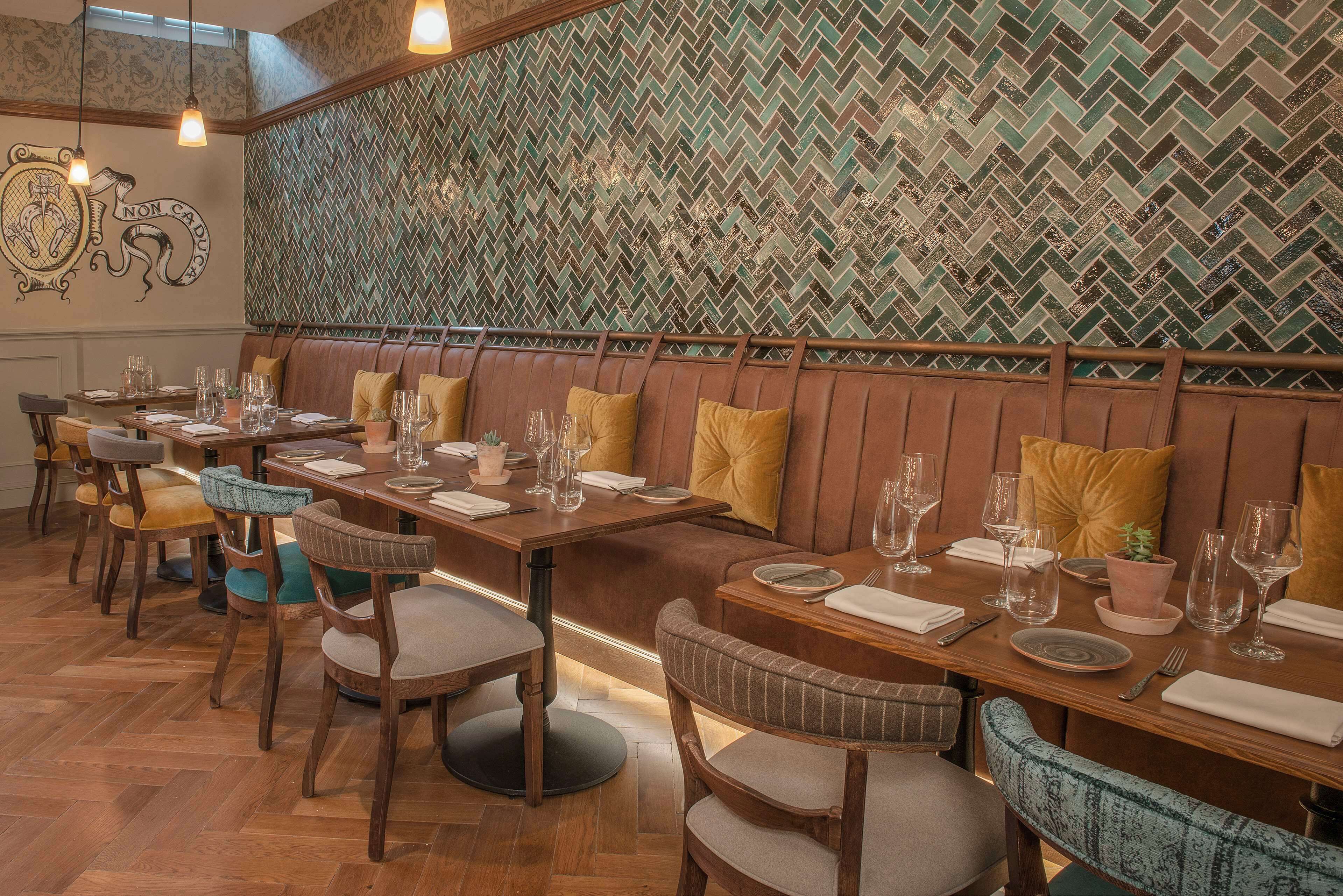 A restaurant interior with wooden tables, cushioned booths, and a patterned wall.