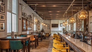 A restaurant interior with wooden flooring, bar seating, and hanging pendant lights. - De Vere Beaumont Estate (Windsor)