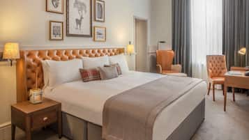 Una habitación de hotel ordenada con una cama grande, dos mesitas de noche, una silla, un escritorio y una lámpara.