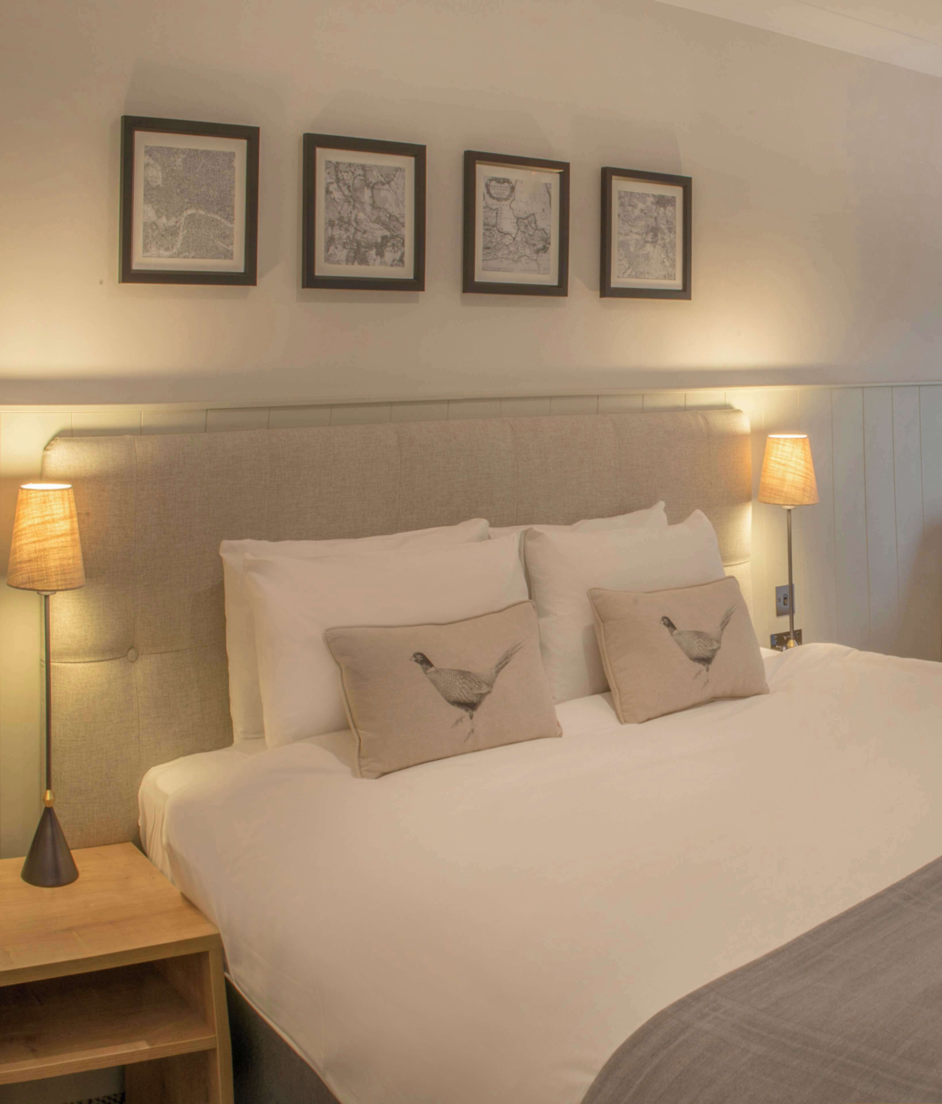 Habitación de hotel con una cama grande, dos lámparas de noche y tres cuadros en la pared.