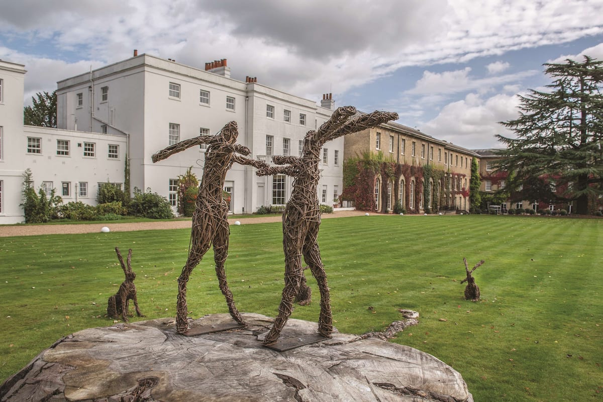 A sculpture of two figures on a large rock in front of a building.