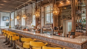 A bar area with a long counter, multiple stools, and hanging light fixtures. - De Vere Beaumont Estate (Windsor)