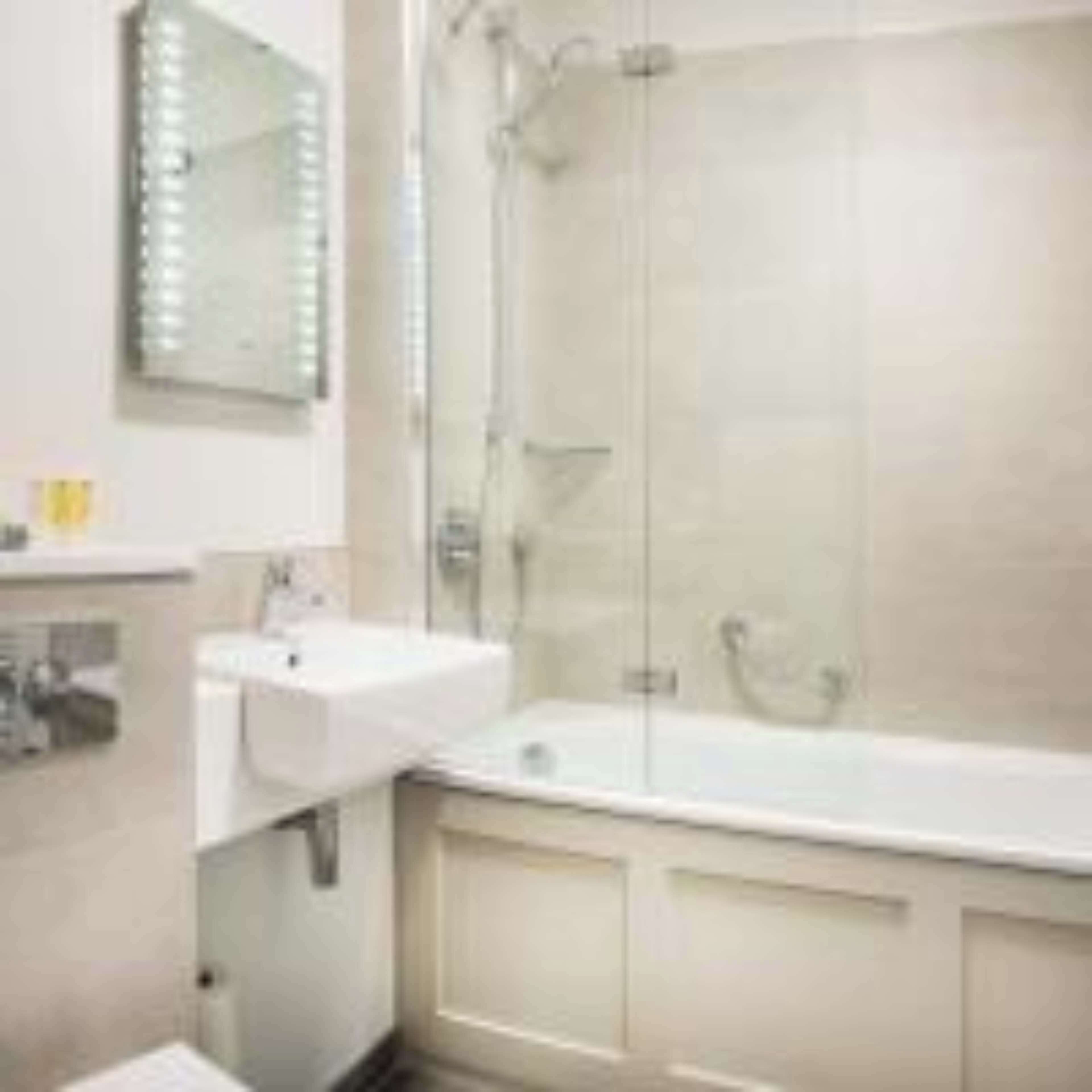 A bathroom with a glass-enclosed shower, a sink, and a mirror.