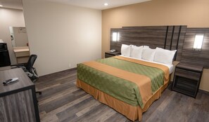 Quarto de hotel com cama, mesas de cabeceira, escrivaninha e uma cadeira.