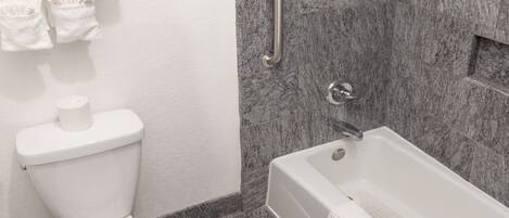 Un baño moderno con inodoro, bañera y zona de ducha.