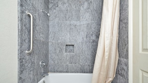 Un baño moderno con bañera, ducha y barra de apoyo.