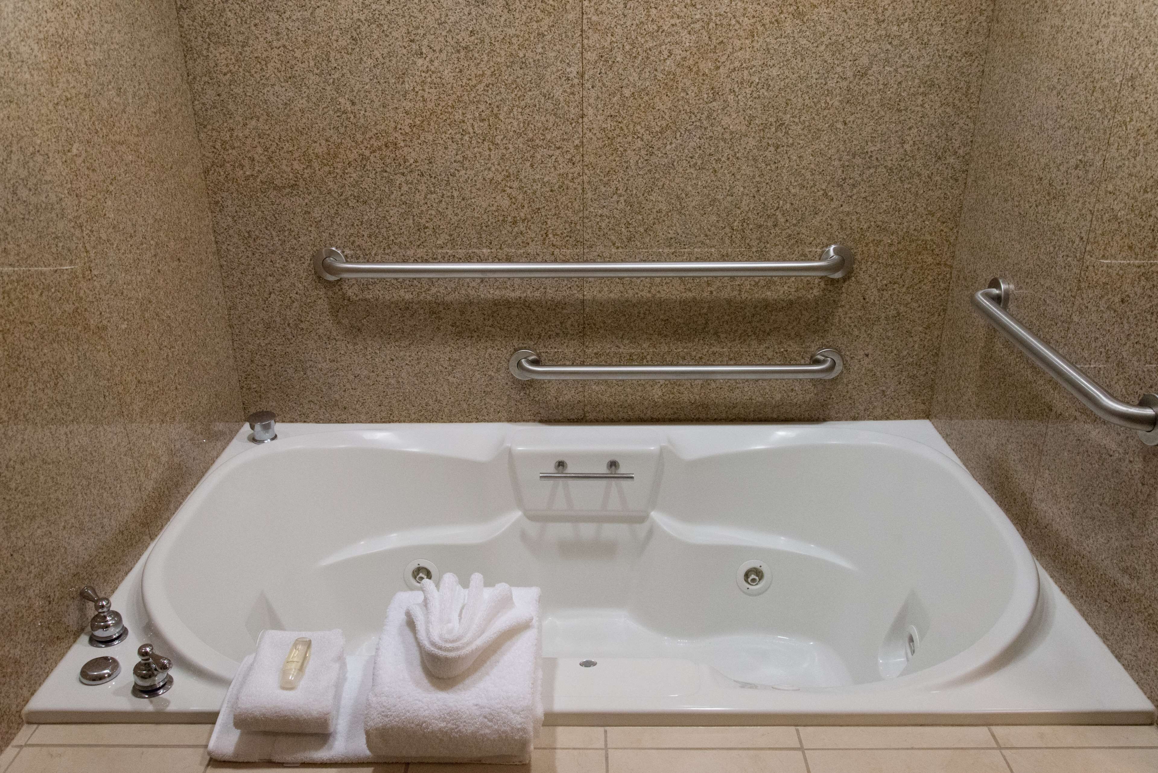 A white bathtub with a grab bar, a towel, and a soap dish.