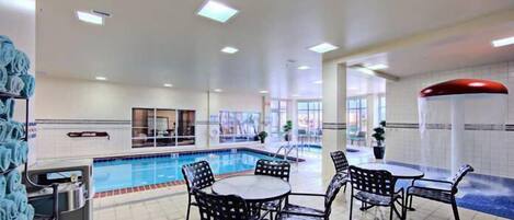 Ein Hallenbad mit gefliesten Wänden, einem Billardtisch und mehreren Sitzgelegenheiten.