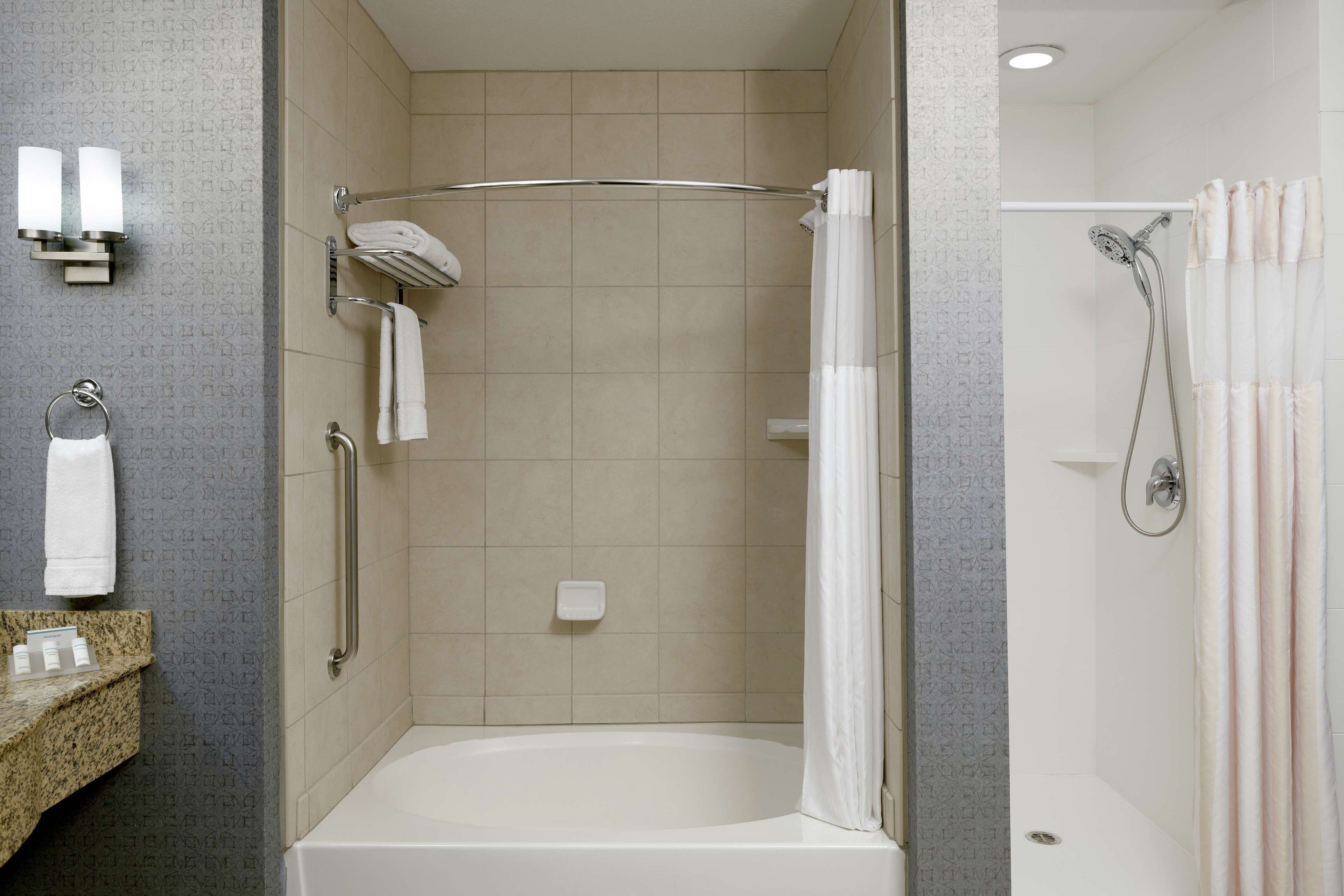 A modern bathroom with a walk-in shower, a bathtub, and a vanity with a towel rack.