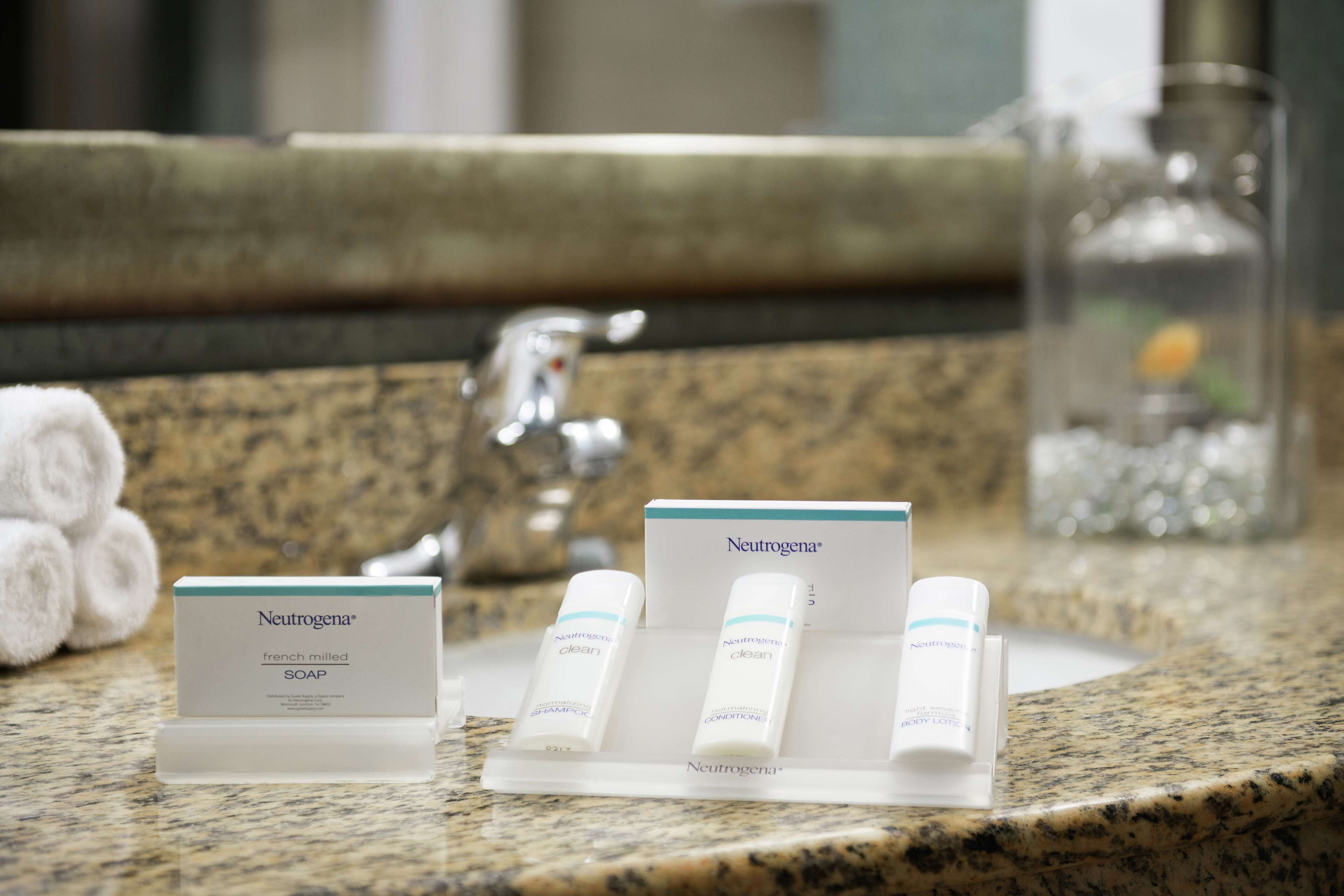 A bathroom counter with a Neutrogena soap dispenser, a body lotion, and a conditioner.