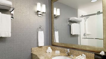 Un baño con lavamanos de encimera de granito, un espejo grande y dos toalleros.