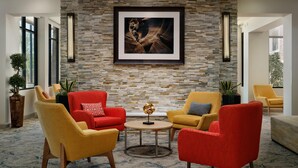 A modern lounge area with stone wall, framed artwork, and comfortable seating. - Hilton Garden Inn Phoenix North Happy Valley (Phoenix)