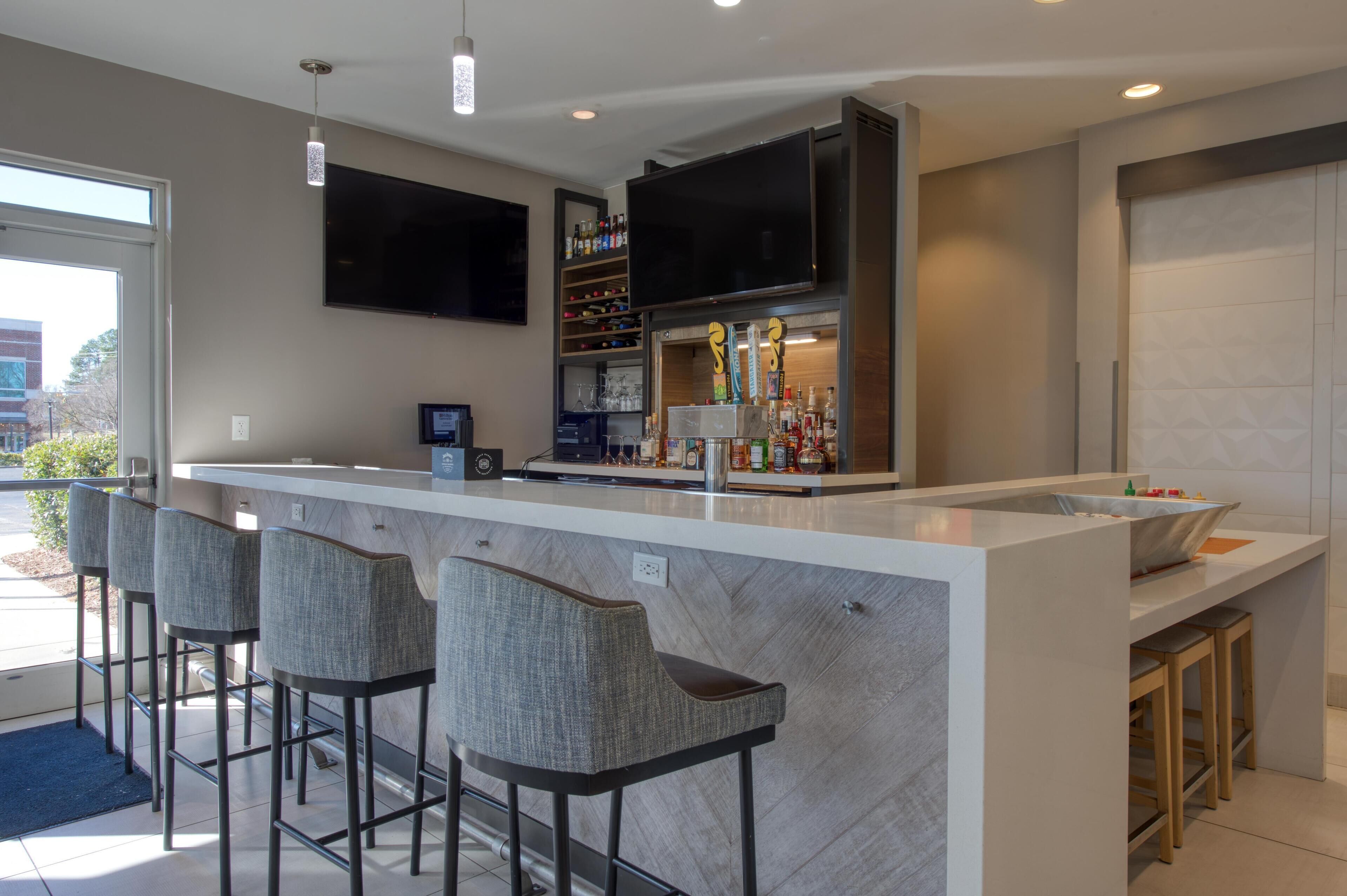 A modern kitchen with a bar area, built-in wine racks, and a large flat-screen TV.