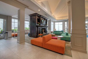 Relax in our inviting lobby, featuring a comfortable sofa, fireplace, and large windows offering views of the outdoors.