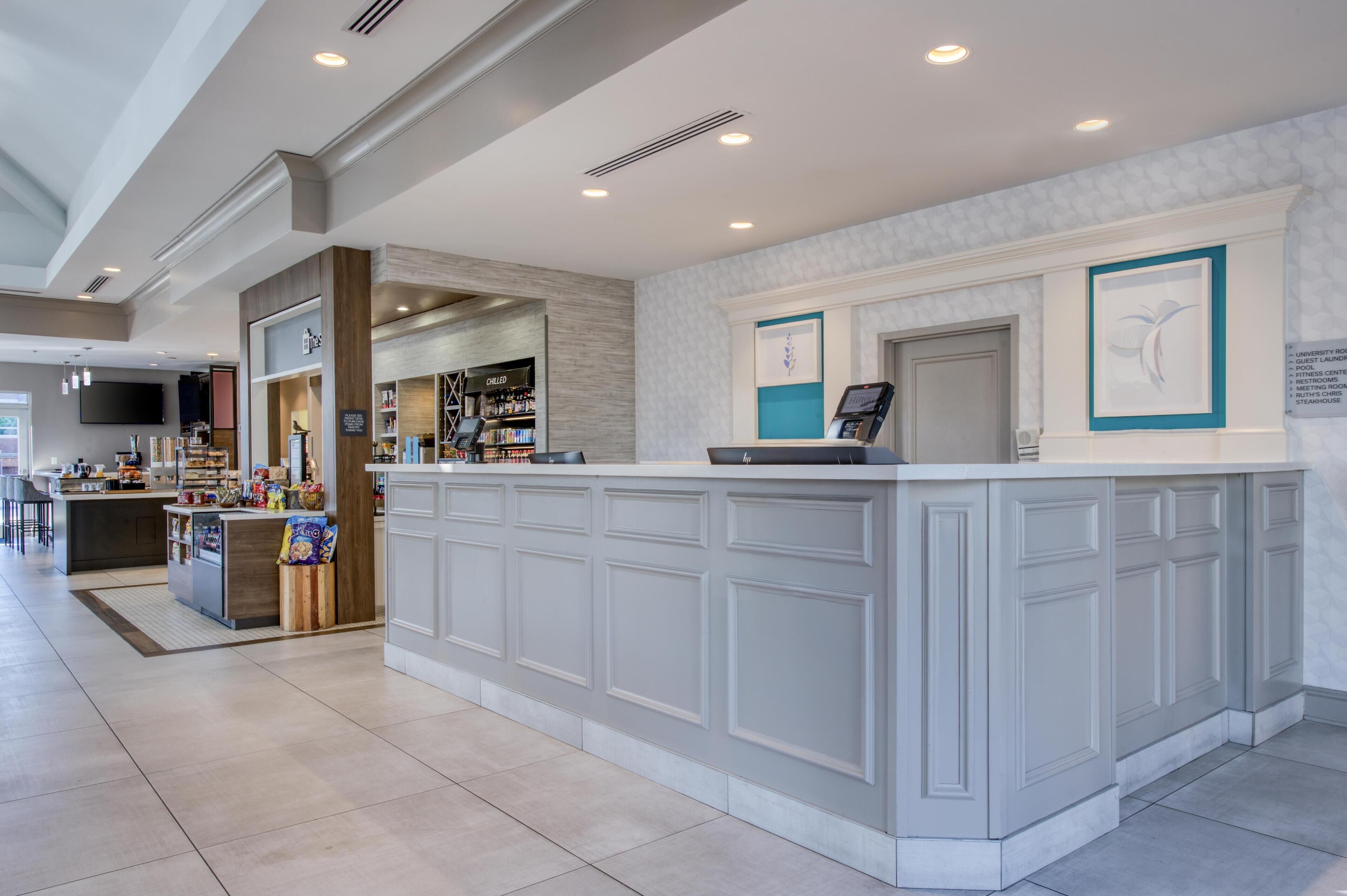 A hotel lobby with a reception desk, a coffee station, and a bar area.