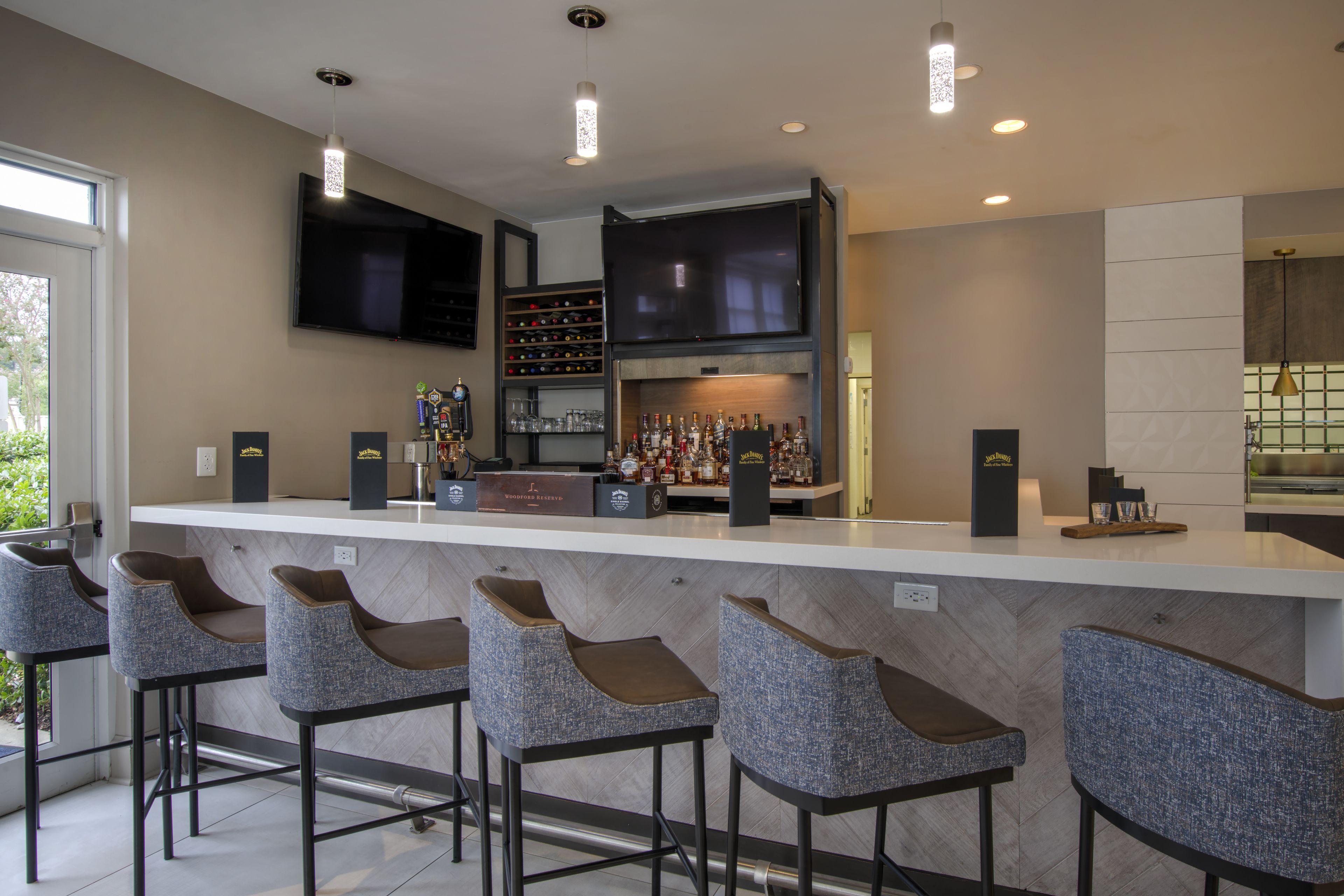 Zona de bar moderna con televisor de pantalla plana, una estantería para vinos y una barra.