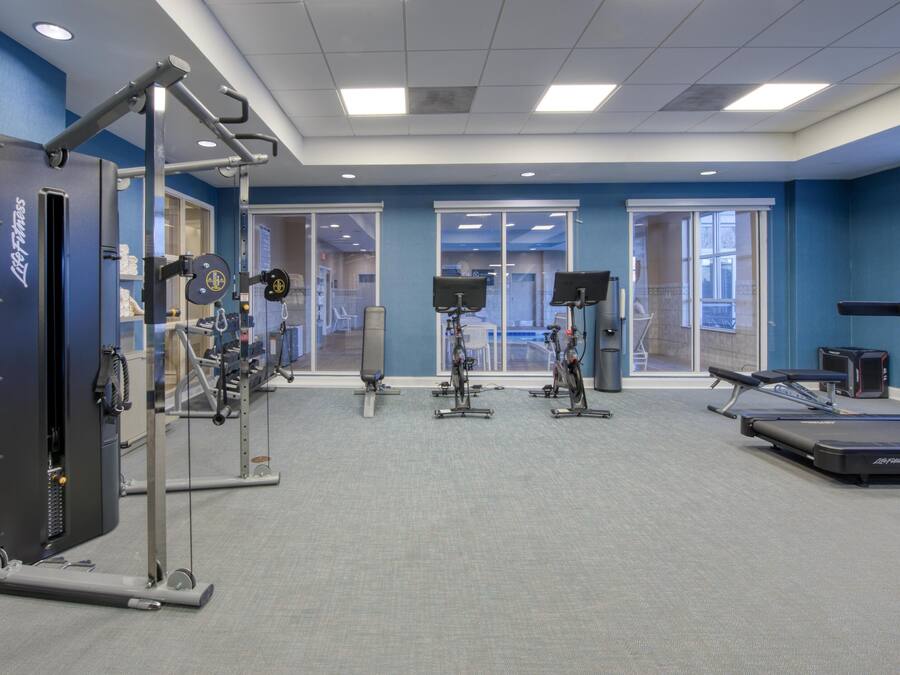 A gym with exercise equipment, large windows, and a blue wall.
