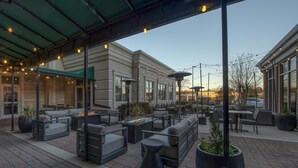 An outdoor patio with modern furniture, including sofas and tables, under a green roof. - Hilton Garden Inn Durham Southpoint (Durham)