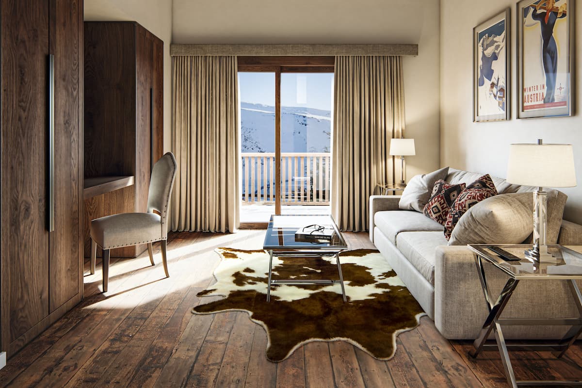 Una sala de estar moderna con piso de madera, un sofá, una mesa de centro y vistas de una montaña nevada a través de amplios ventanales.