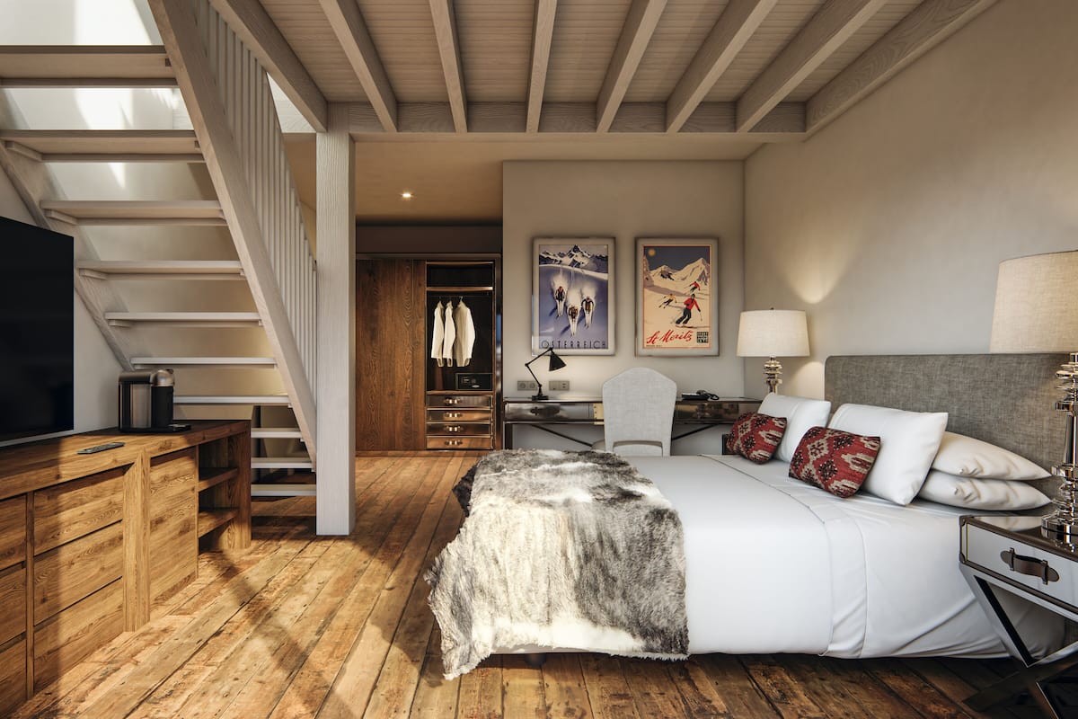 Un dormitorio con una escalera de madera, una cama con almohadillas estampadas, un escritorio con una lámpara y un televisor sobre un mueble de madera.