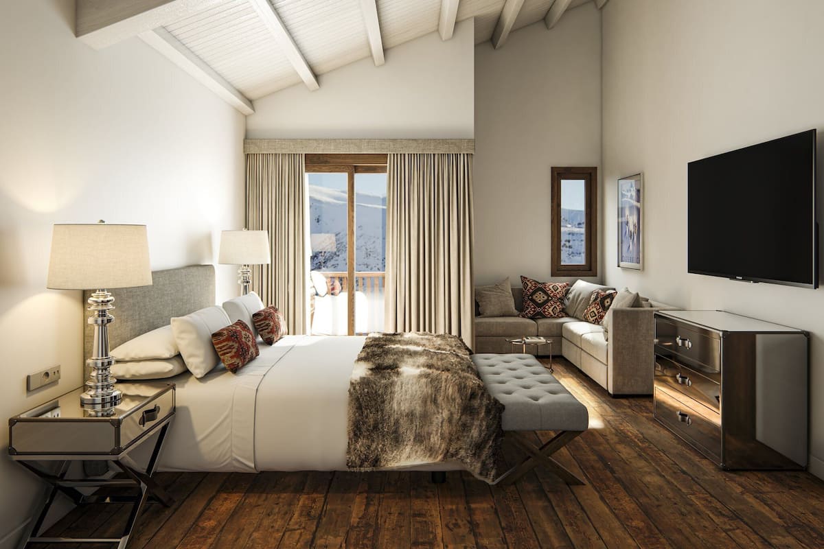Un dormitorio amplio con una cama grande, un sofá, un televisor y piso de madera.