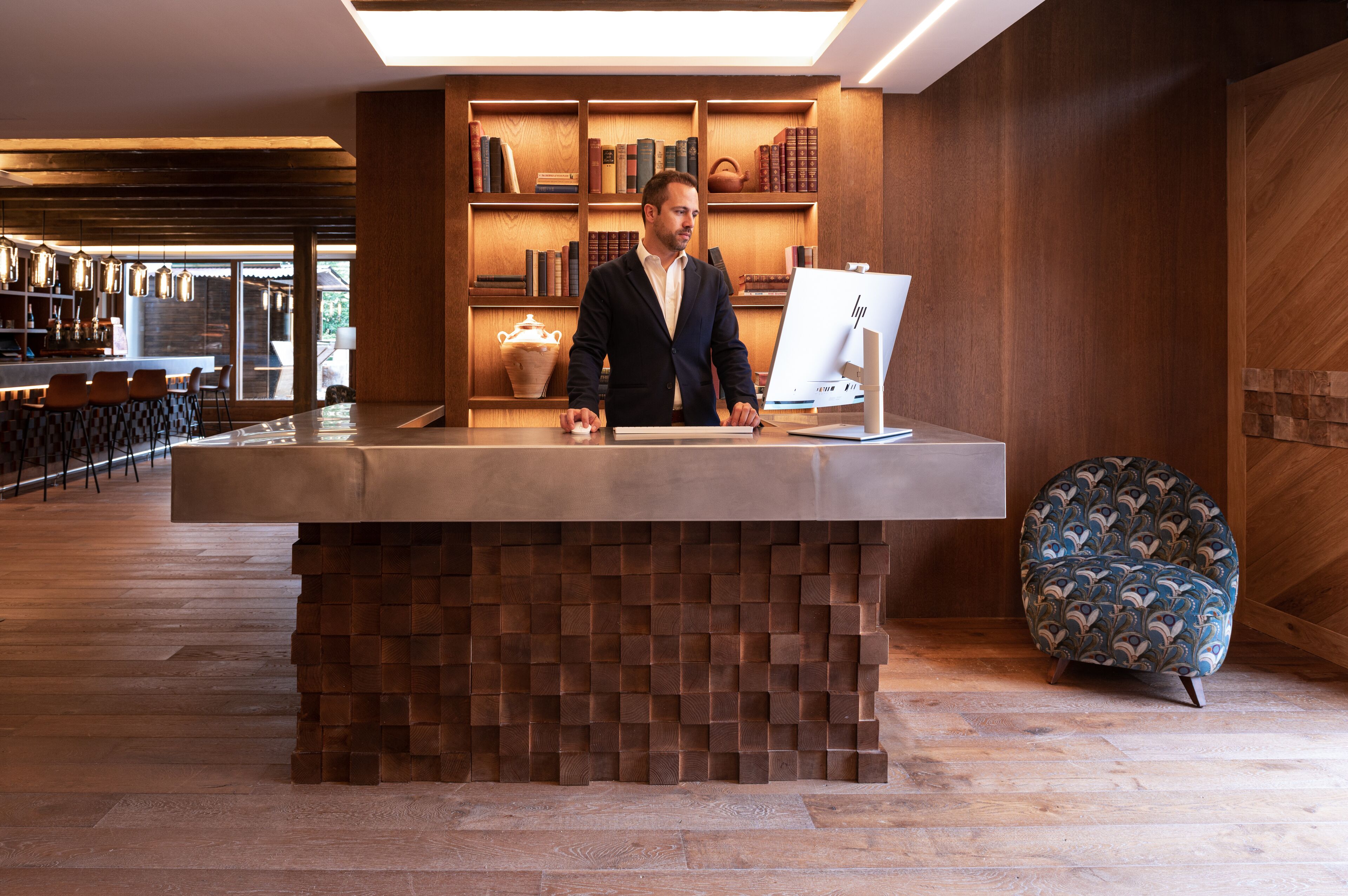 A reception desk with a modern design, wooden bookshelves, and a seating area with patterned chairs.