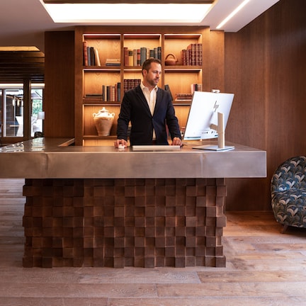 A reception desk with a modern design, wooden bookshelves, and a seating area with patterned chairs.