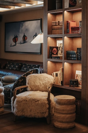 A cozy reading nook with a plush chair, a wooden bookshelf, and a framed artwork on the wall.
