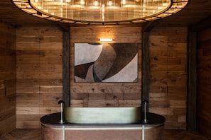 A wooden interior with a round sink and a wall-mounted light fixture.