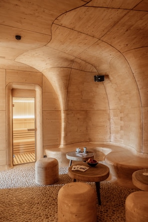 A wooden interior with a curved ceiling, a small table with a bowl, and a bench.