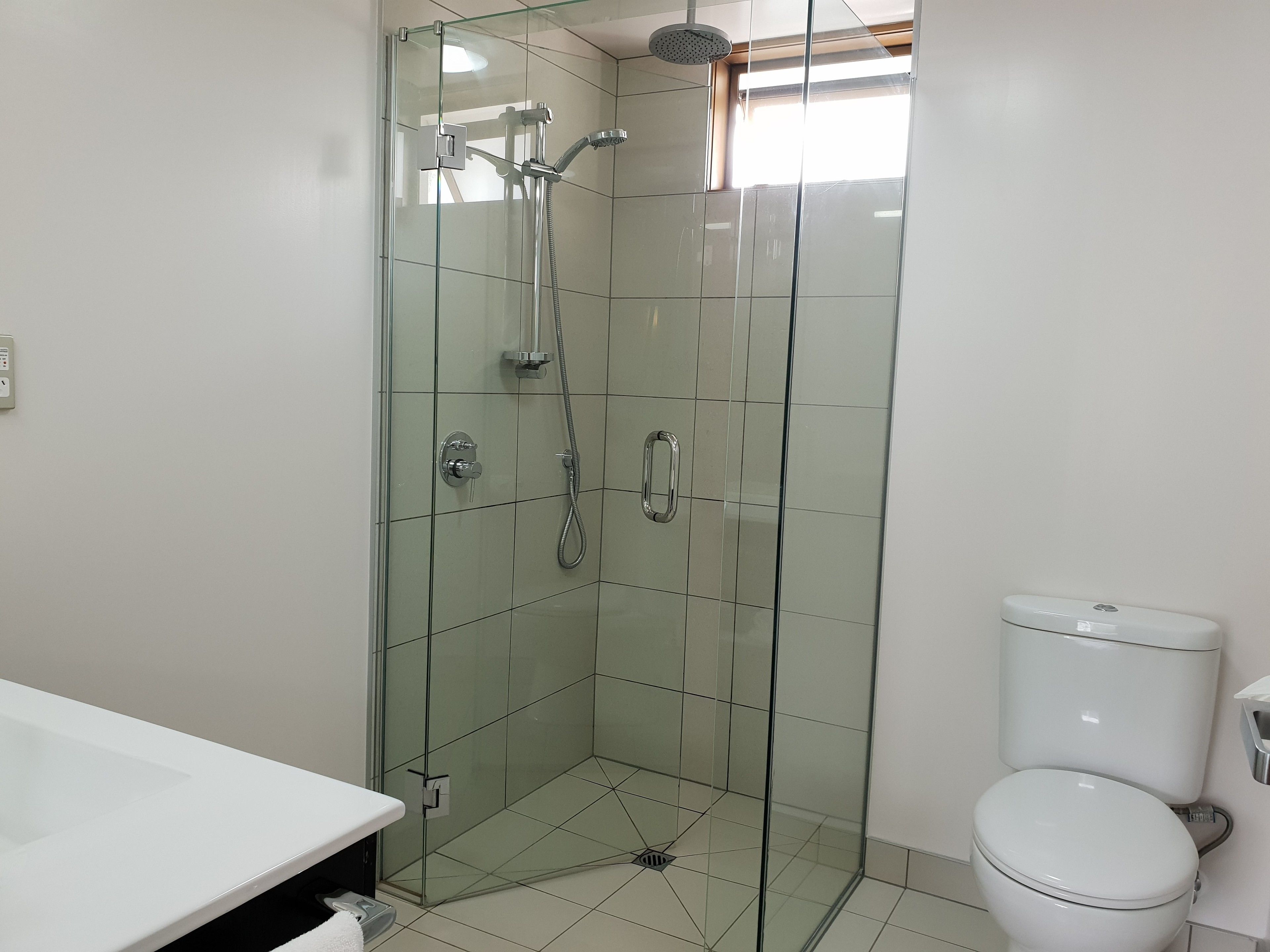 Une salle de bain avec une douche à parois de verre, des toilettes et un lavabo blanc.