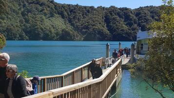 A wooden pier extending into a lake, surrounded by lush green hills.