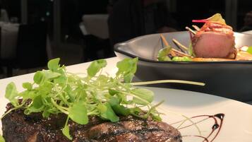 A steak with greens on a plate, in a restaurant setting.