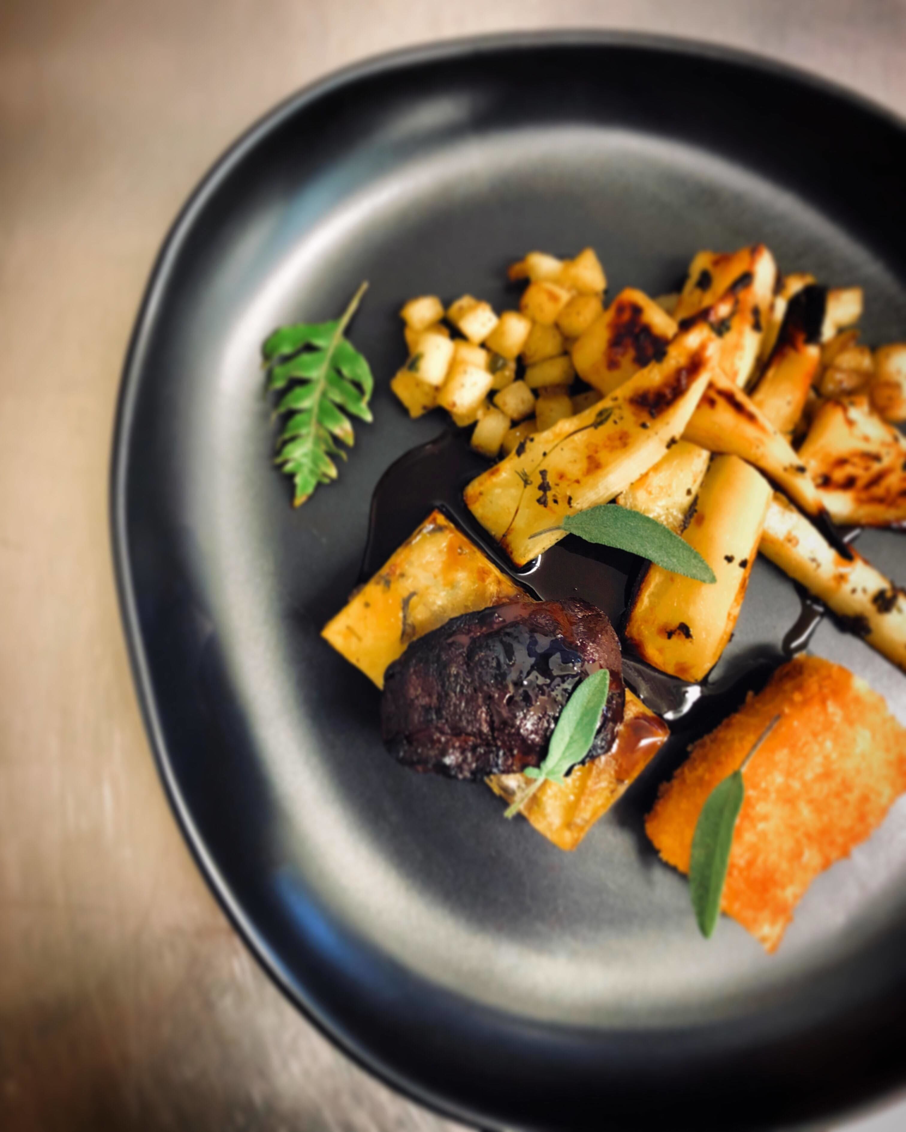 A plate with roasted potatoes, a piece of meat, and a garnish.