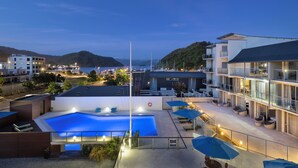 Un hotel moderno con piscina sul tetto, area salotto esterna e vista sul mare e sulle colline.