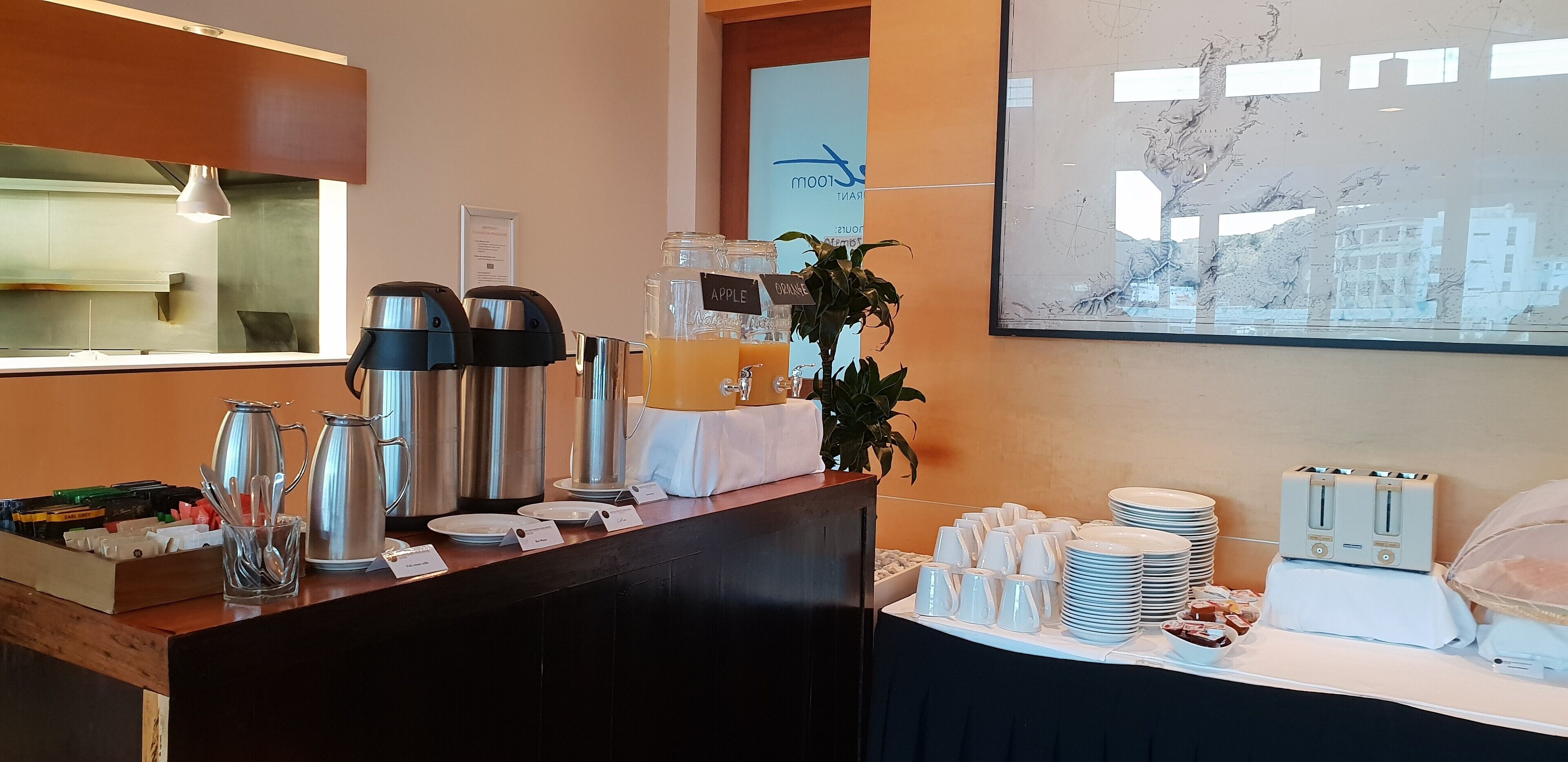 A breakfast bar with coffee makers, juice dispensers, and a fruit display.