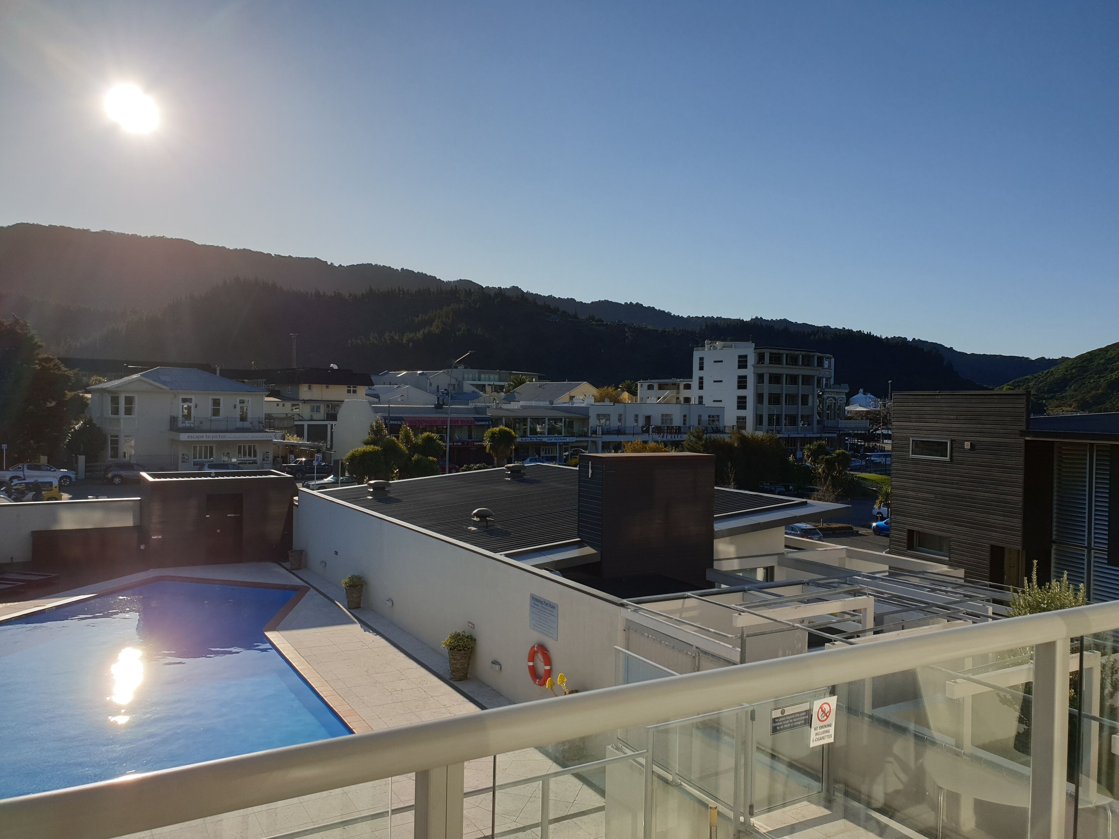 Una piscina en la azotea con vistas despejadas a edificios circundantes y una montaña al fondo.
