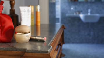 Una encimera de baño con un tarro de crema, un lápiz labial y un bolso rojo.