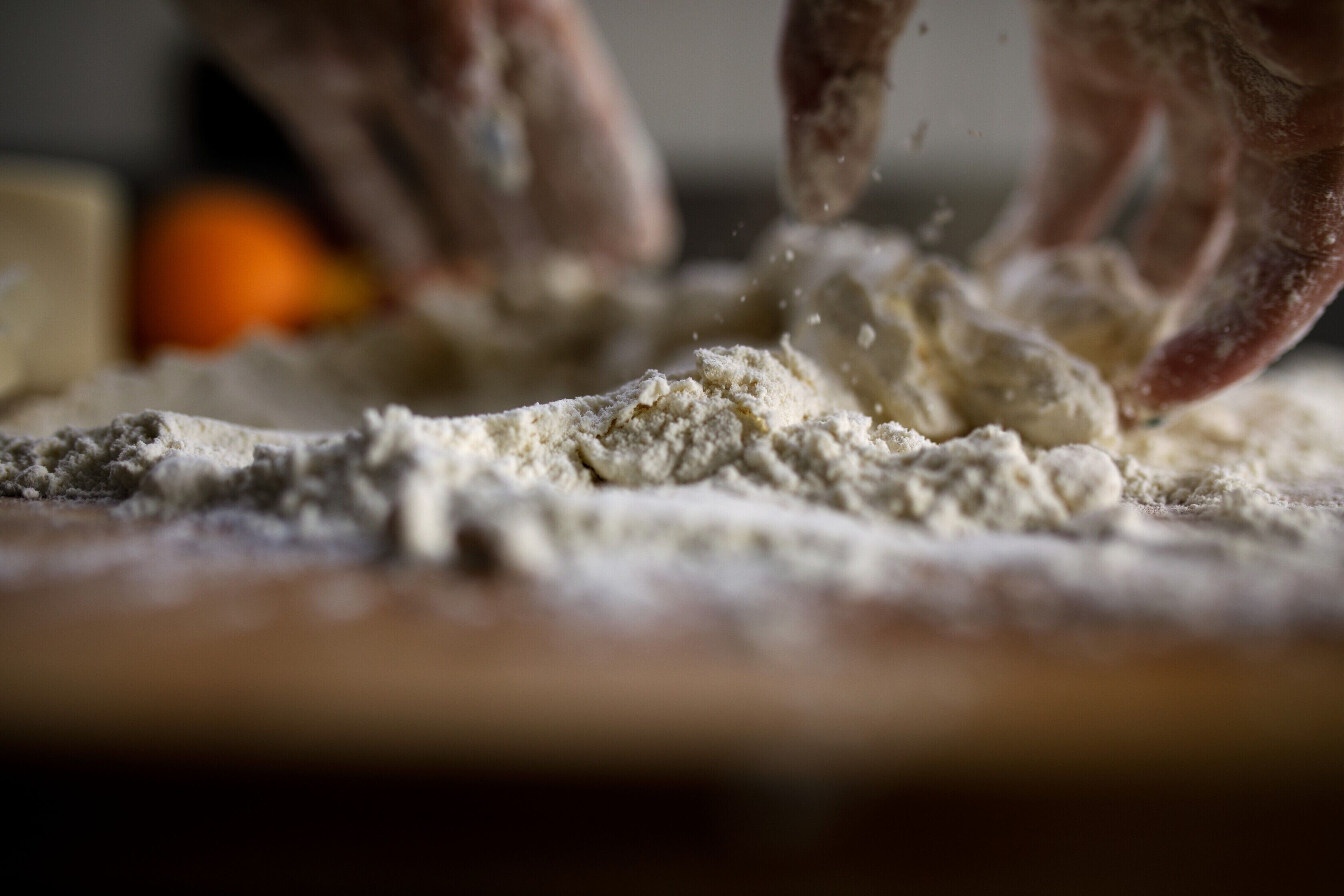 Hands sprinkling flour on a surface.