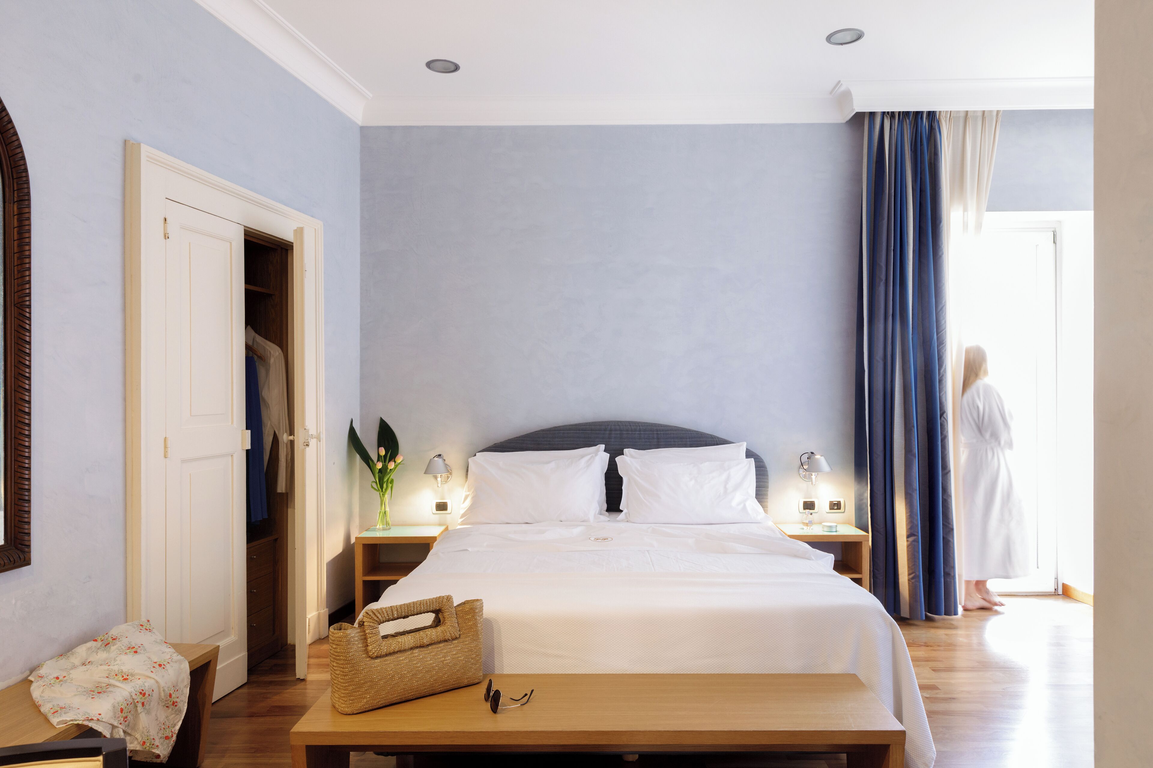 A bedroom with a bed, bedside tables, a bench, and a wardrobe.