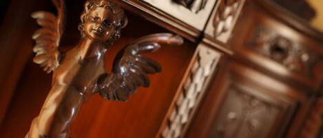 A wooden cabinet with intricate carvings and a decorative angel figure.