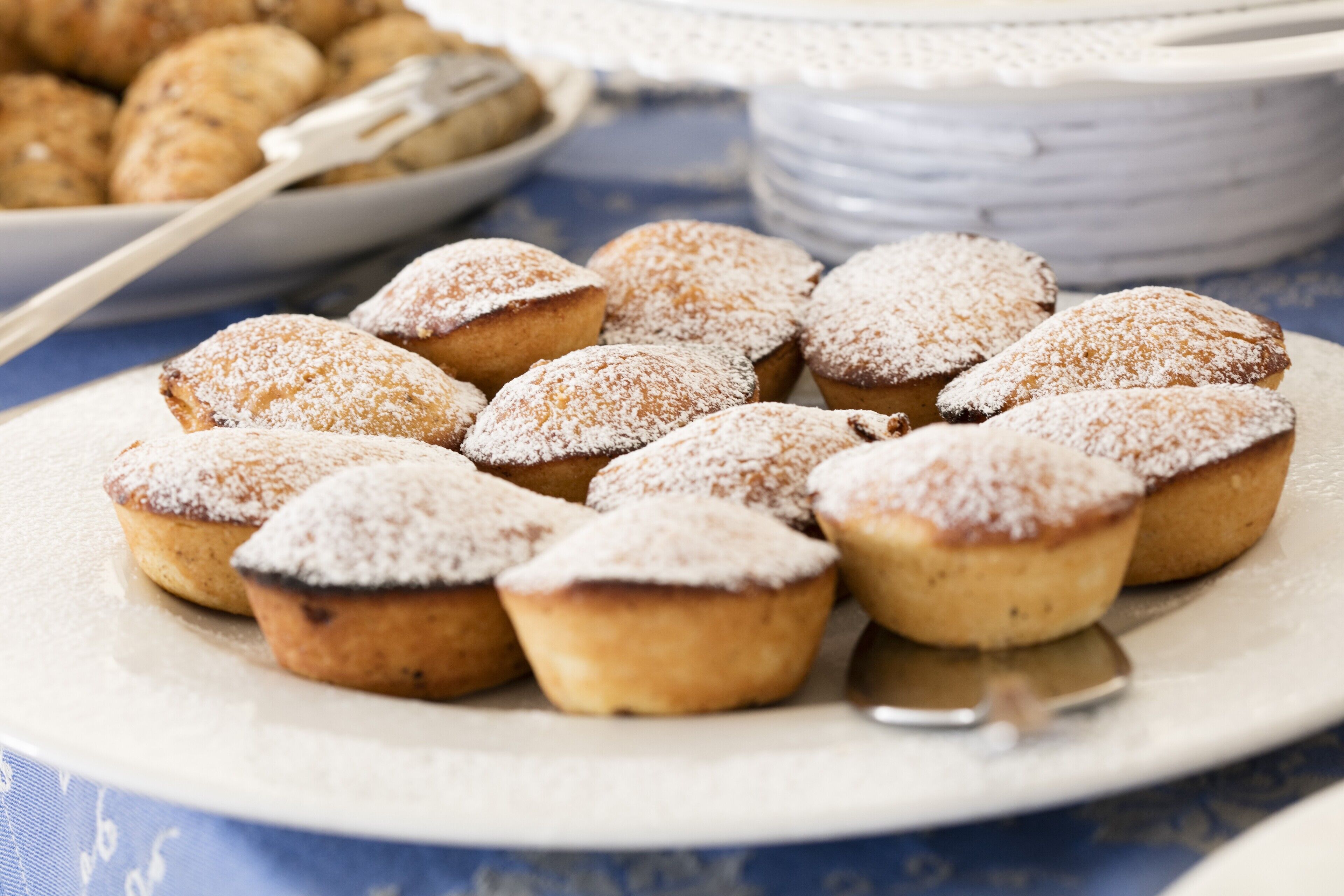 A plate of muffins with powdered sugar on a table.
