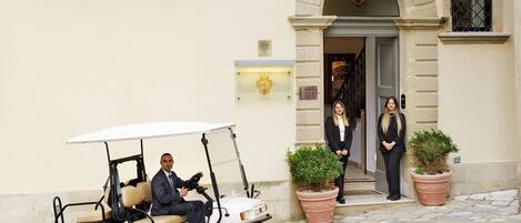 A building with a double balcony, a golf cart, and potted plants.