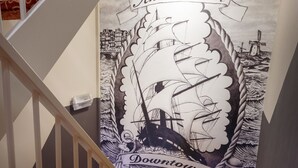 A staircase with a red patterned carpet and a mural of a ship and the text "Amsterdam Downtown Hotel". - Amsterdam Downtown Hotel (Amsterdam)