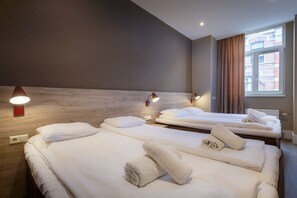 A hotel room with three beds, each with neatly folded towels and pillows. - Amsterdam Downtown Hotel (Amsterdam)