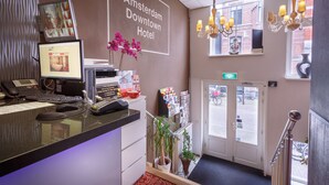 A hotel reception desk with a computer, phone, and a sign reading "Amsterdam Downtown Hotel". - Amsterdam Downtown Hotel (Amsterdam)