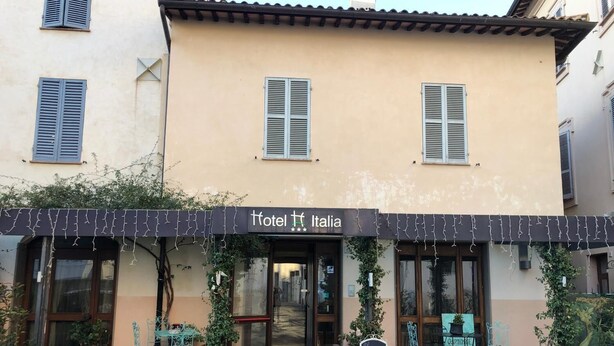 A building with a sign reading "Hotel Italia" and outdoor seating with chairs and tables. - Hotel Italia (Foligno)