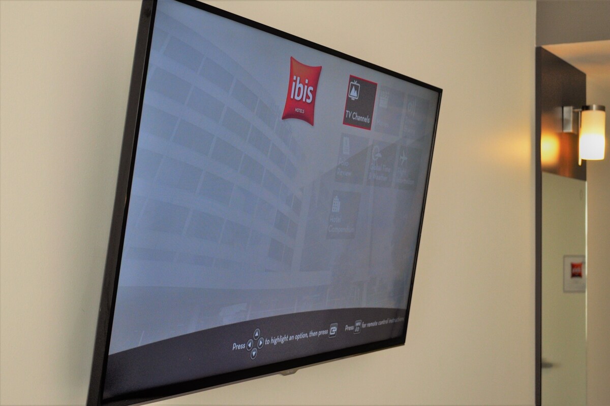 Un écran de télévision d’hôtel affichant le logo d’Ibis et les chaînes de télévision.