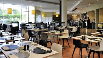 Un'elegante sala da pranzo moderna con tavoli apparecchiati per quattro, completa di posate e bicchieri, e un'area bar sullo sfondo.
