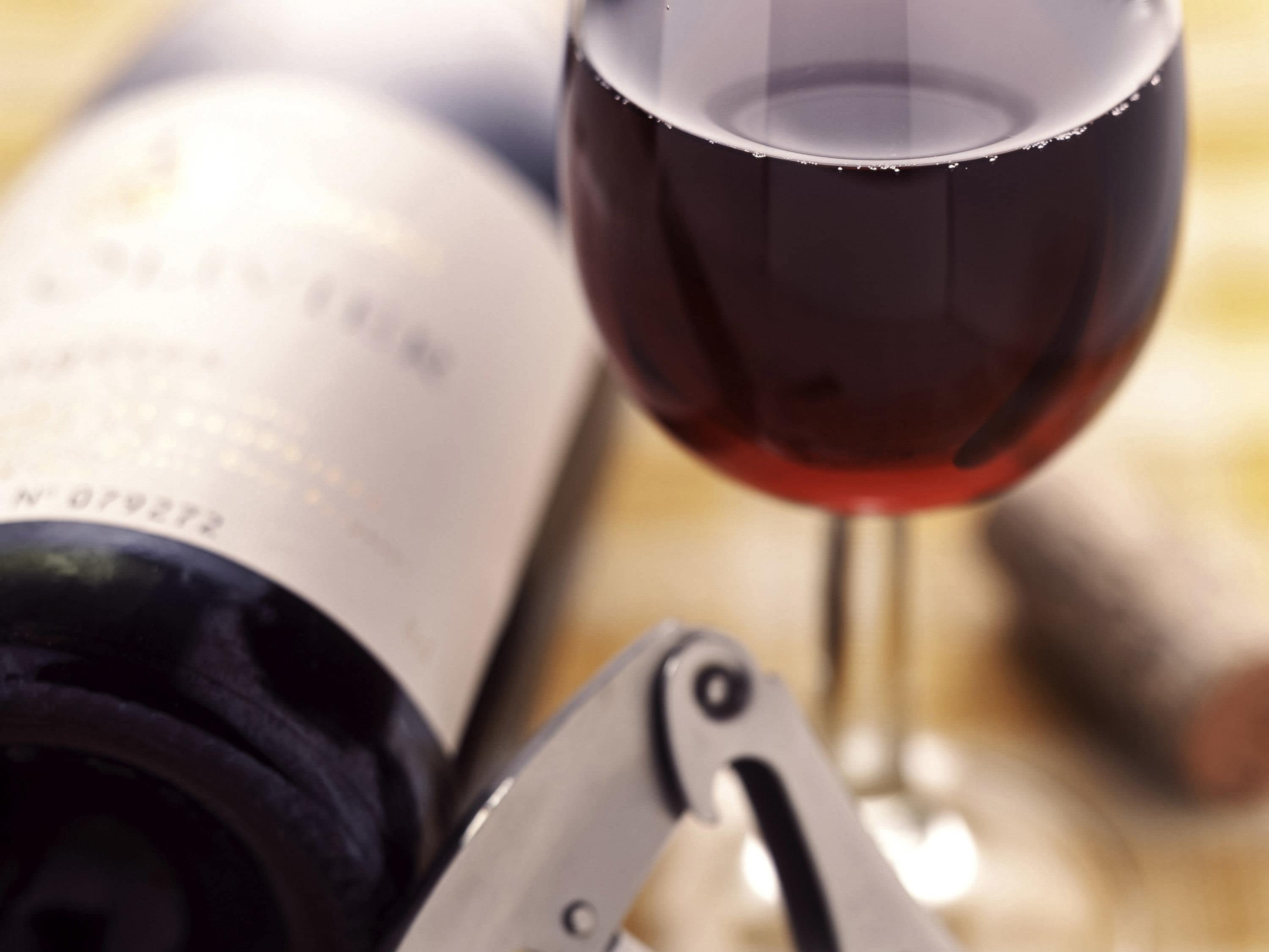 Una botella de vino, una copa de vino y un sacacorchos.